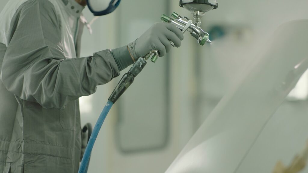 Professional auto painter applying flawless white paint spray at Mas Chingon Bodyshop Terrell